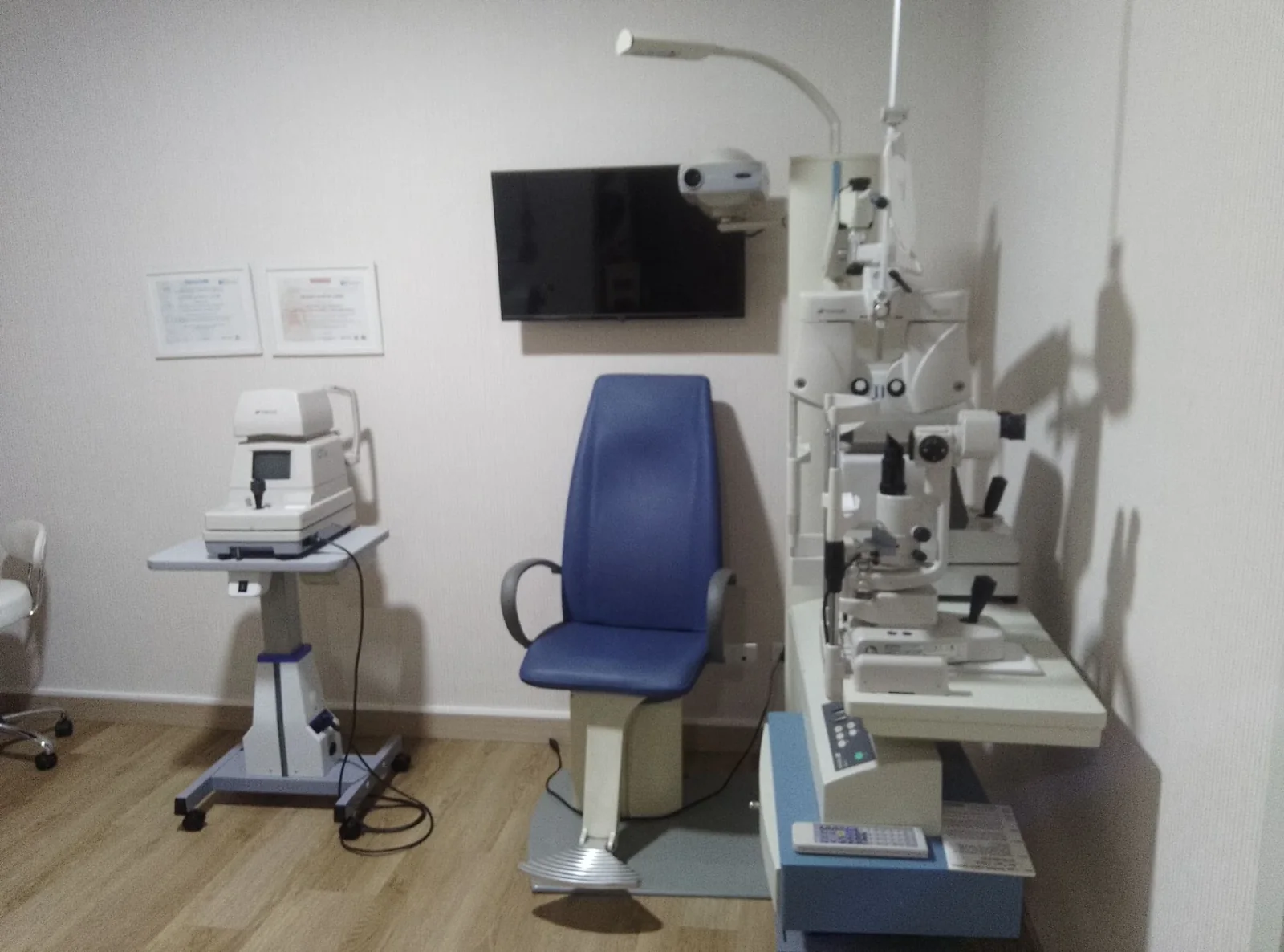 Sala de exploración con sillón de paciente, lámpara de hendidura, proyector de optotipos y tonómetro